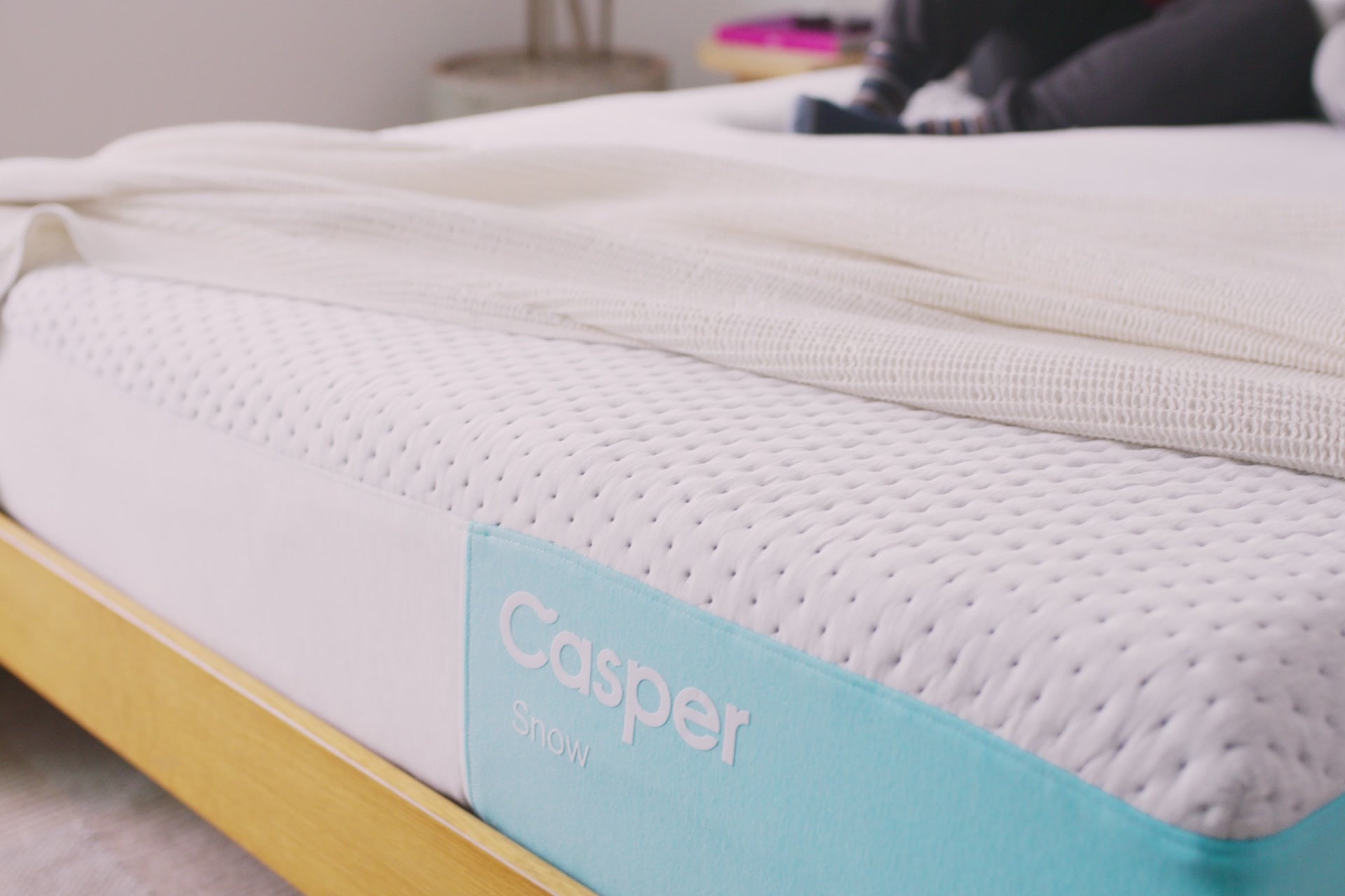 Video of a couple sitting against a wooden headboard on their Snow cooling mattress.