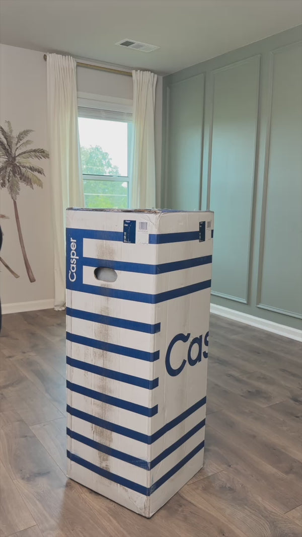 Person unboxing the Casper One mattress and placing on bedframe