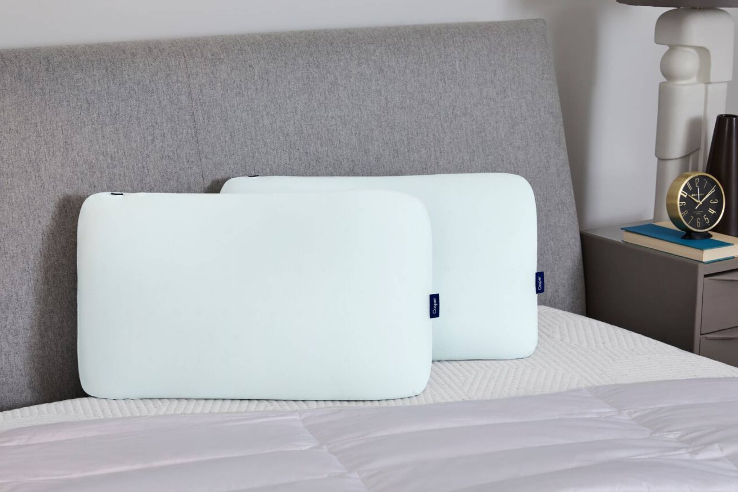 Two Hybrid Snow Pillows leaning back against a headboard.